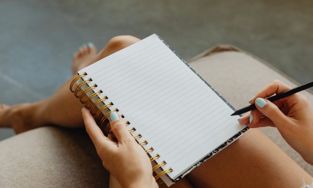 woman holding a spiral notebook and pen
