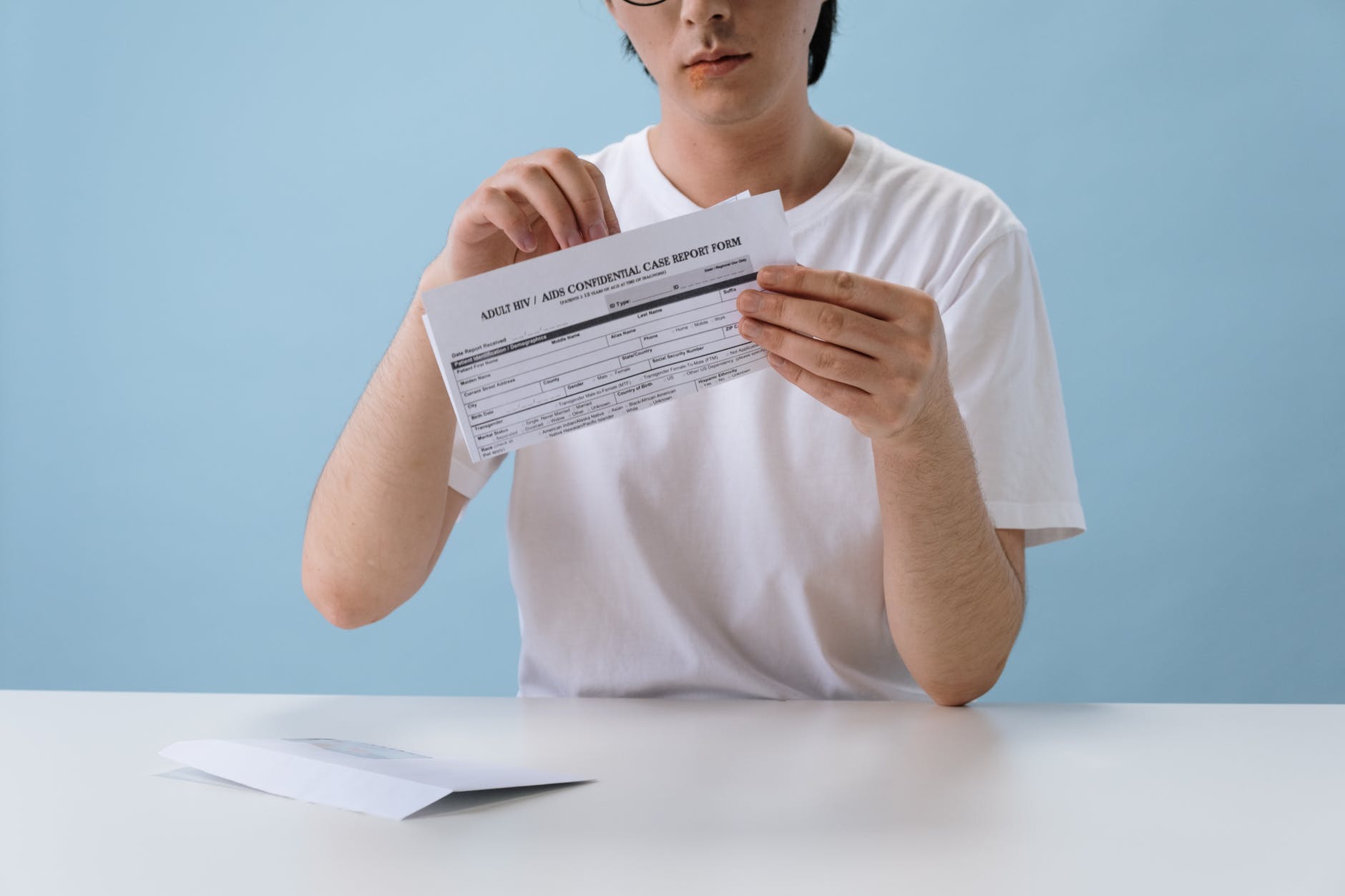 man in white t shirt holding hiv aids paper form